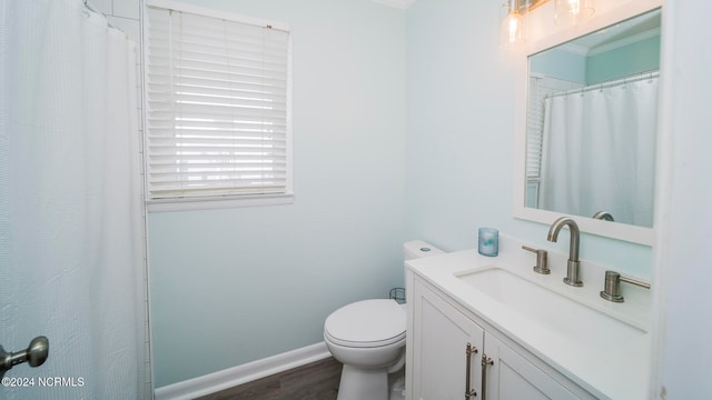 bathroom featuring toilet, vanity, baseboards, and wood finished floors