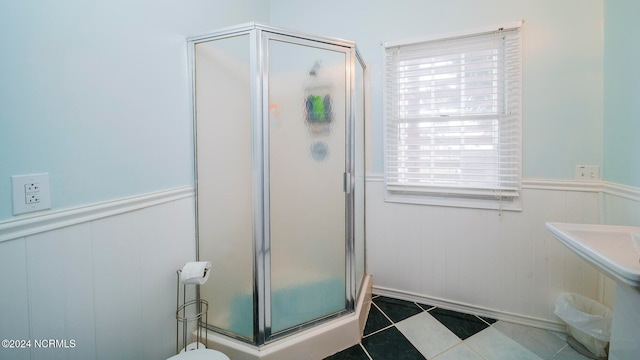 full bathroom featuring a wainscoted wall, a stall shower, and tile patterned flooring