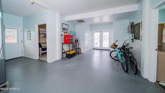 foyer with french doors, visible vents, concrete flooring, and wainscoting