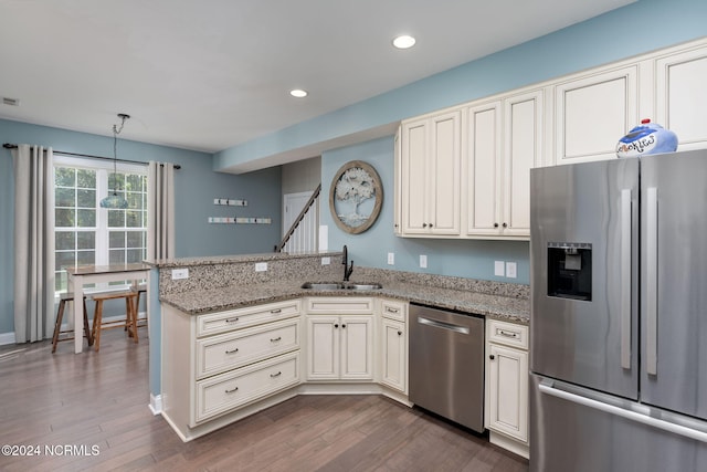 kitchen featuring sink, light stone countertops, pendant lighting, and appliances with stainless steel finishes