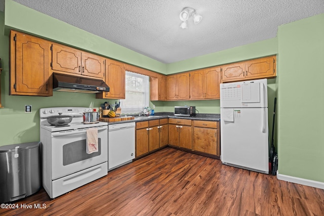 kitchen with white appliances, dark hardwood / wood-style floors, a textured ceiling, and sink