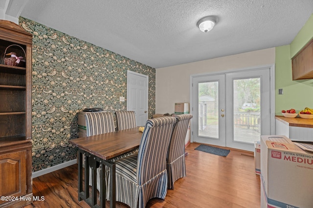 dining room featuring french doors, wood-type flooring, and a textured ceiling