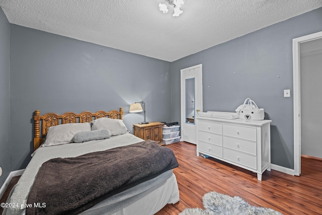 bedroom with light hardwood / wood-style floors and a textured ceiling