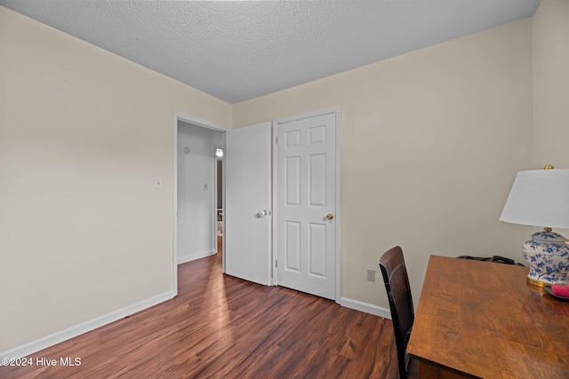 unfurnished office with dark wood-type flooring and a textured ceiling