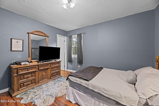 bedroom with wood-type flooring and a textured ceiling