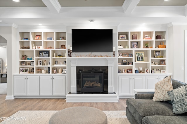 living room with a tile fireplace, ornamental molding, beam ceiling, and light hardwood / wood-style flooring