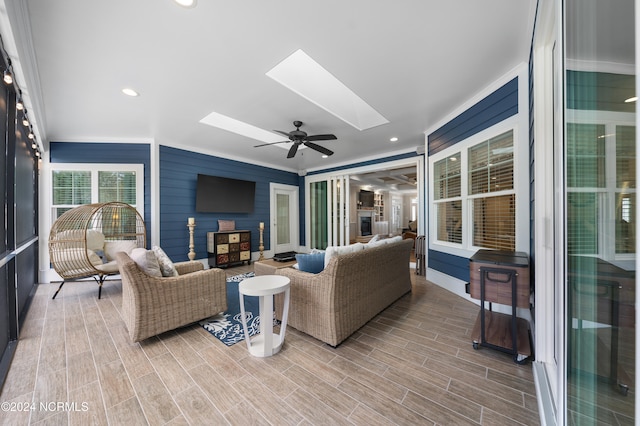 living room with ceiling fan, a skylight, and hardwood / wood-style flooring