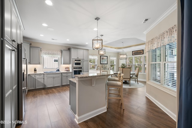 kitchen with hanging light fixtures, a center island with sink, dark hardwood / wood-style floors, and a kitchen breakfast bar