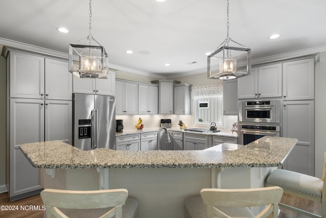 kitchen with appliances with stainless steel finishes, a large island, pendant lighting, and light stone counters