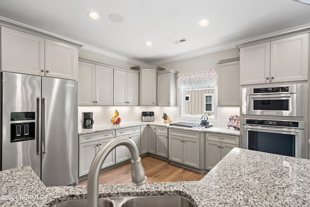 kitchen with backsplash, sink, stainless steel appliances, and light stone countertops