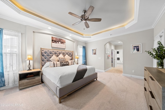 bedroom with ornamental molding, a tray ceiling, ceiling fan, and light carpet