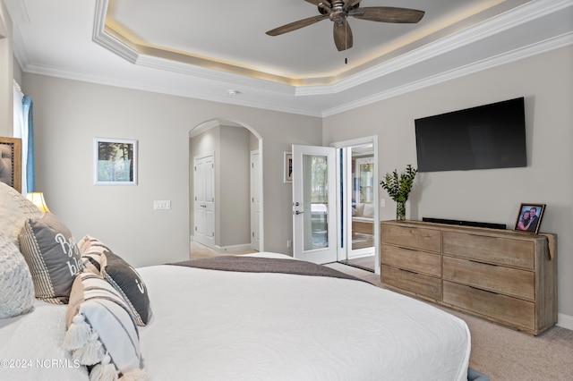 carpeted bedroom featuring a raised ceiling, ornamental molding, and ceiling fan