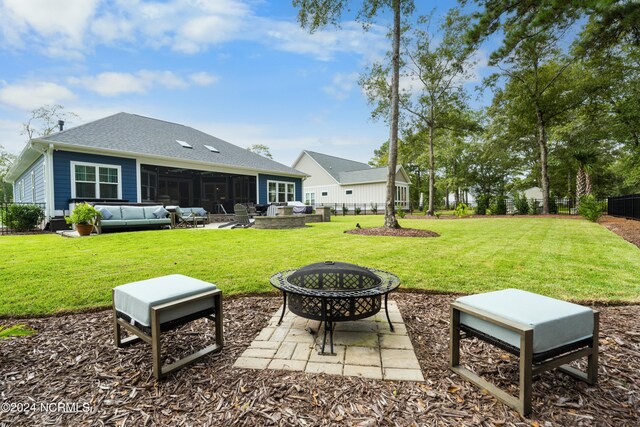 rear view of property with an outdoor living space with a fire pit, a lawn, and a patio