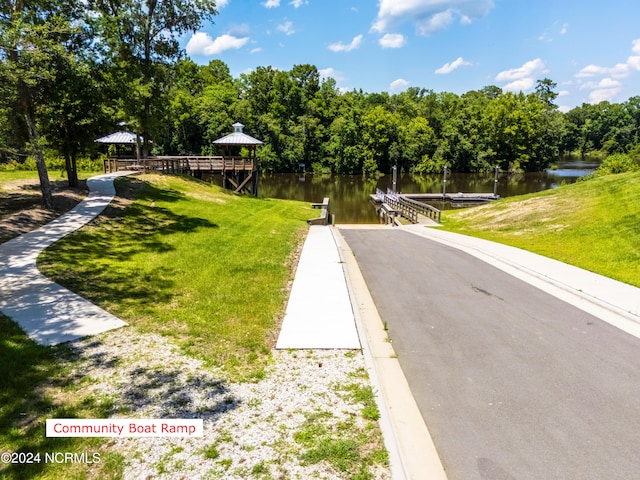 view of community with a boat dock, a water view, and a yard