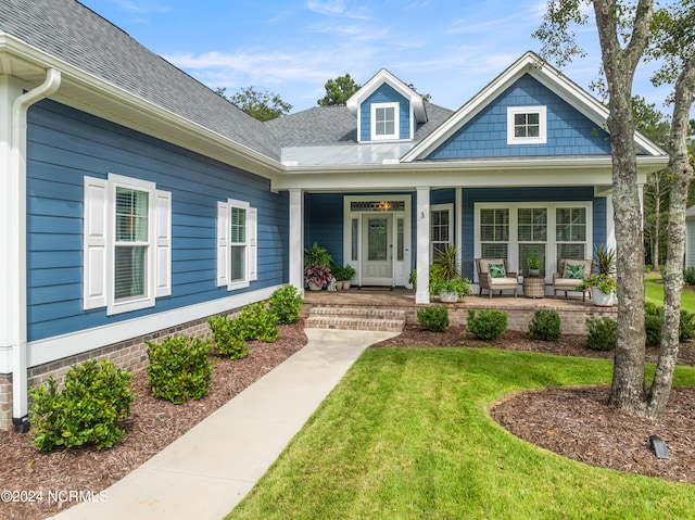 entrance to property with covered porch and a yard