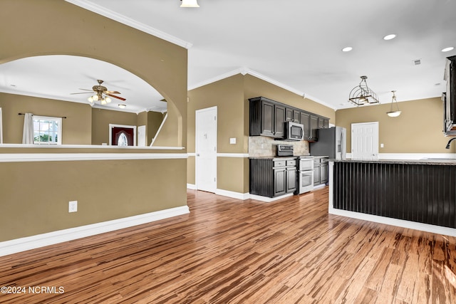 kitchen featuring appliances with stainless steel finishes, crown molding, sink, light hardwood / wood-style floors, and hanging light fixtures