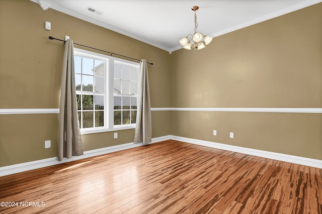 spare room featuring light wood-type flooring, ornamental molding, and a chandelier