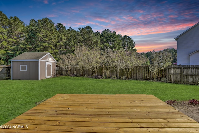 deck at dusk featuring a shed and a yard