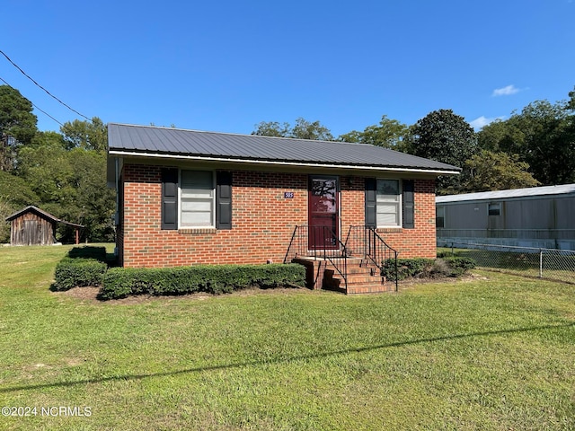 view of front of house featuring a storage shed and a front yard