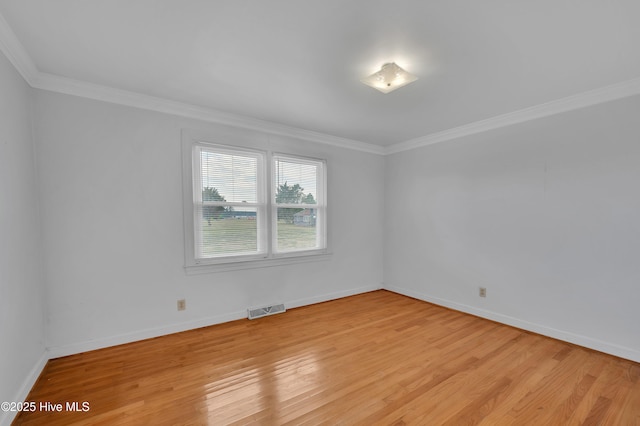 spare room with baseboards, light wood finished floors, visible vents, and crown molding