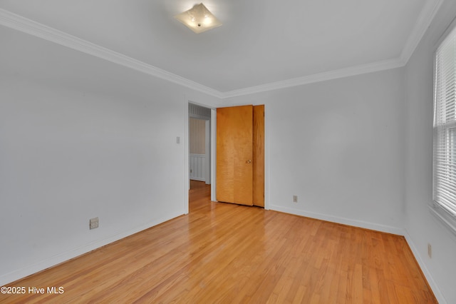 unfurnished room featuring light wood finished floors, baseboards, and crown molding