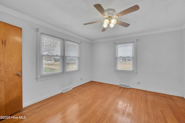 spare room with light wood-style floors, visible vents, and plenty of natural light