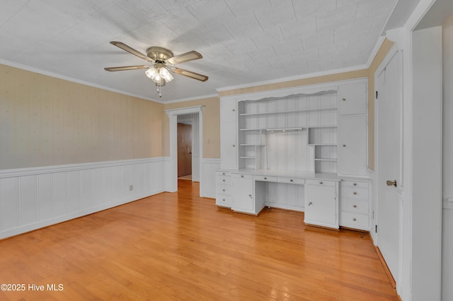 unfurnished bedroom with ornamental molding, light wood-type flooring, wainscoting, and ceiling fan