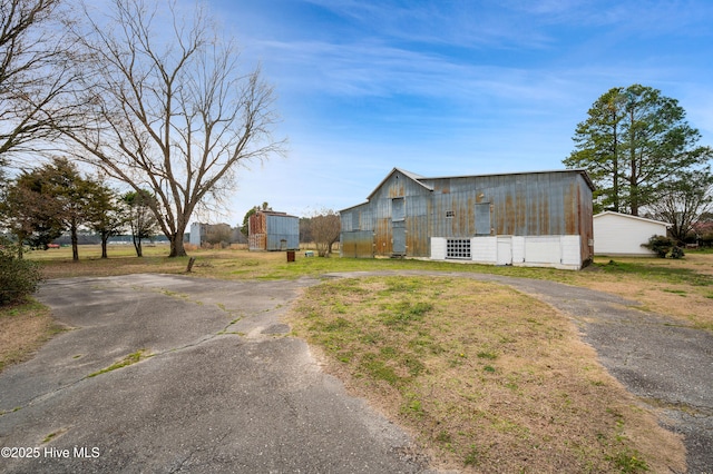 view of front of house with driveway, a pole building, and an outdoor structure