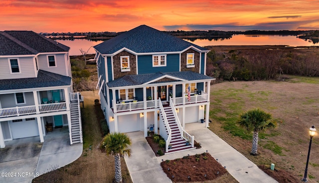 view of front of property with covered porch, a garage, and a water view