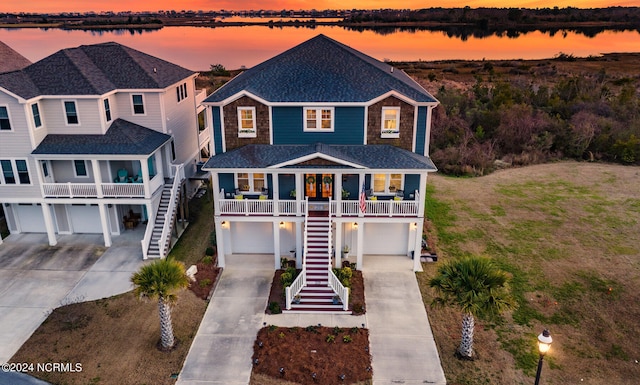 view of front of property featuring a water view, a porch, and a garage