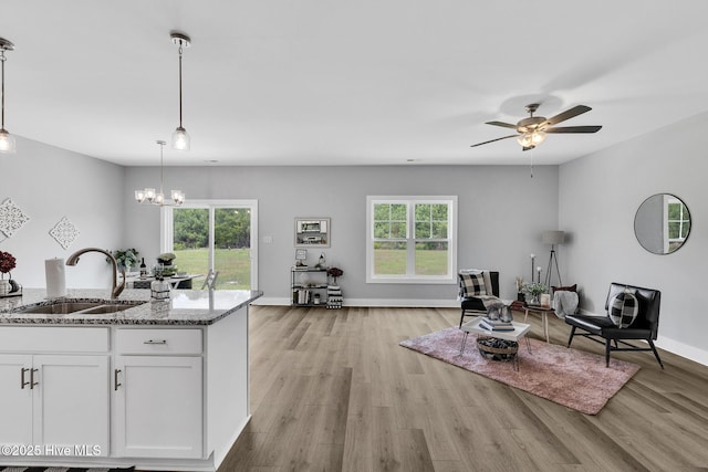 1399 Hammocks Beach Rd, Swansboro, NC 28584 - kitchen with a sink, light stone counters, white cabinetry, ceiling fan, and hanging light fixtures