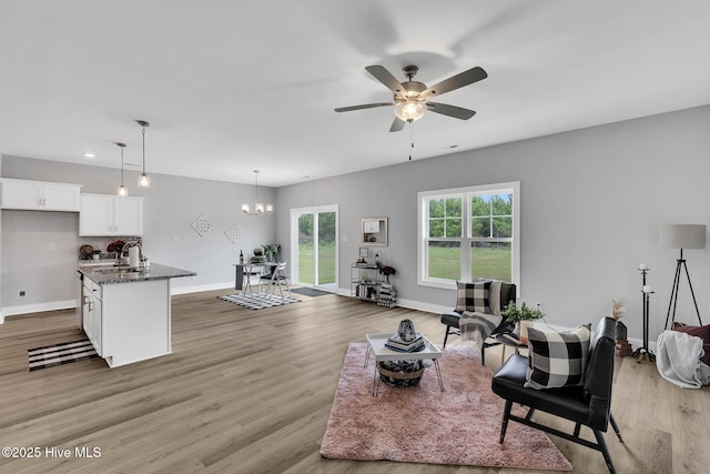 1399 Hammocks Beach Rd, Swansboro, NC 28584 - living area featuring light wood-style flooring, ceiling fan, baseboards, and a chandelier