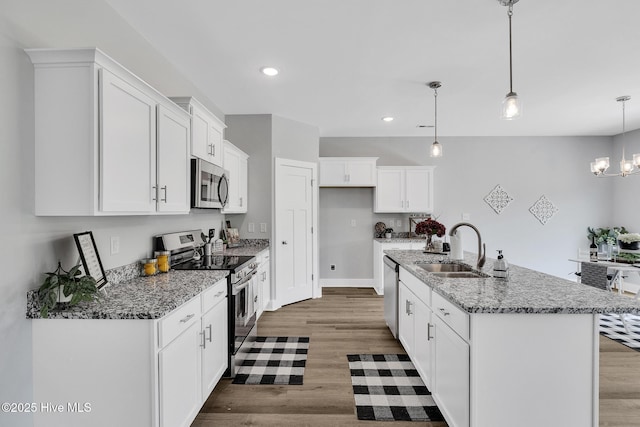 1399 Hammocks Beach Rd, Swansboro, NC 28584 - kitchen with stainless steel appliances, a sink, wood finished floors, white cabinetry, and light stone counters