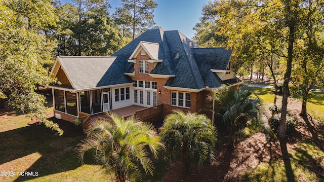 back of property featuring a sunroom and a lawn