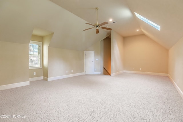 additional living space featuring light carpet, vaulted ceiling with skylight, and ceiling fan