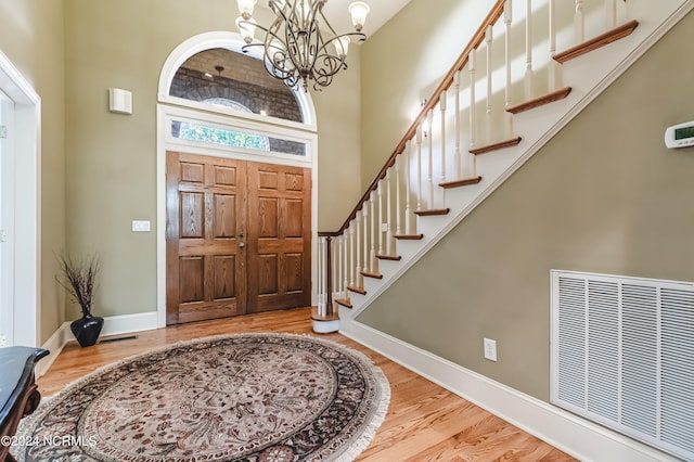 entrance foyer featuring a towering ceiling, light hardwood / wood-style flooring, and an inviting chandelier