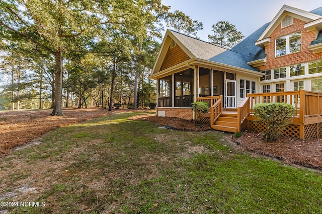 rear view of house featuring a deck, a lawn, and a sunroom