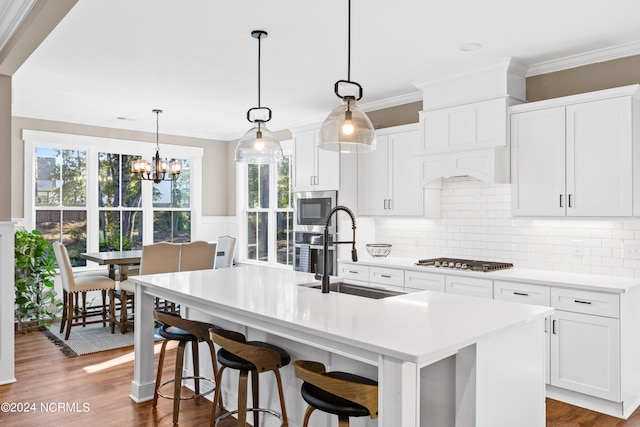 kitchen featuring hanging light fixtures, stainless steel appliances, a kitchen island with sink, and sink