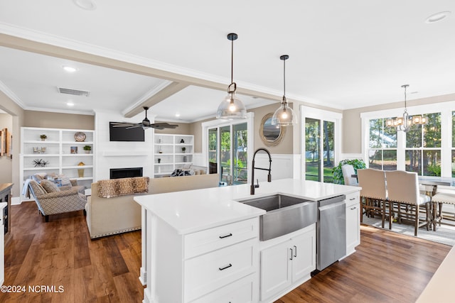 kitchen with dishwasher, a center island with sink, sink, hanging light fixtures, and a large fireplace