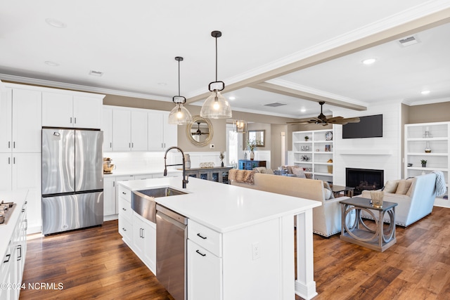 kitchen featuring sink, a fireplace, an island with sink, white cabinetry, and stainless steel appliances