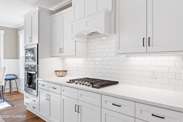 kitchen featuring tasteful backsplash, ornamental molding, stainless steel appliances, dark hardwood / wood-style floors, and white cabinetry