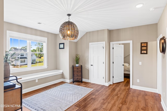 interior space with wood-type flooring, vaulted ceiling, and an inviting chandelier