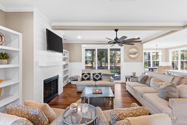 living room with a fireplace, ceiling fan with notable chandelier, dark wood-type flooring, and crown molding