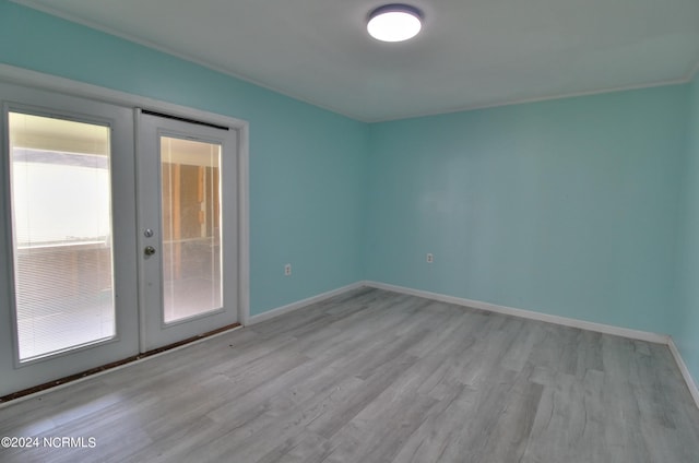 unfurnished room with french doors and light wood-type flooring