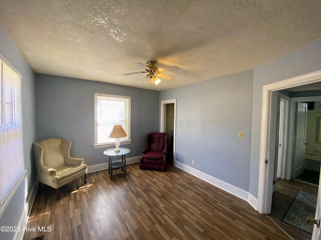 sitting room with dark wood-style floors, a ceiling fan, baseboards, and a textured ceiling