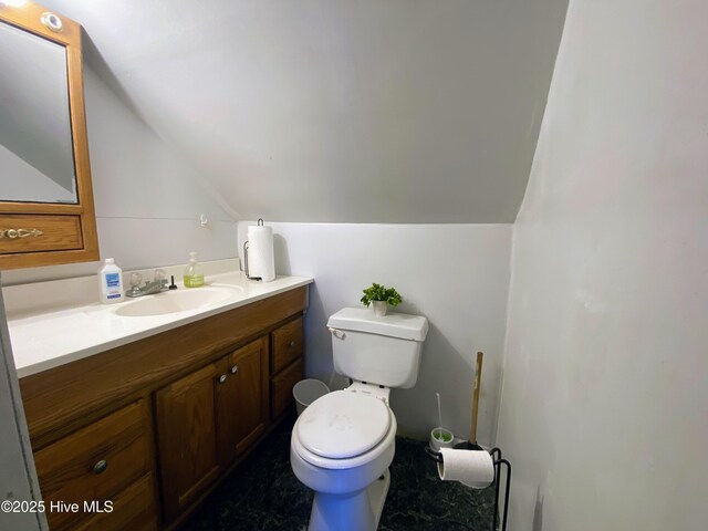 bathroom featuring lofted ceiling, toilet, and vanity