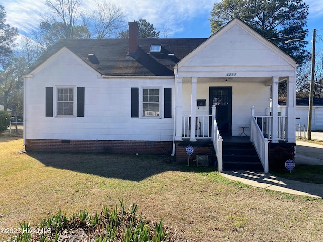 view of front facade with roof with shingles, a chimney, a porch, crawl space, and a front lawn