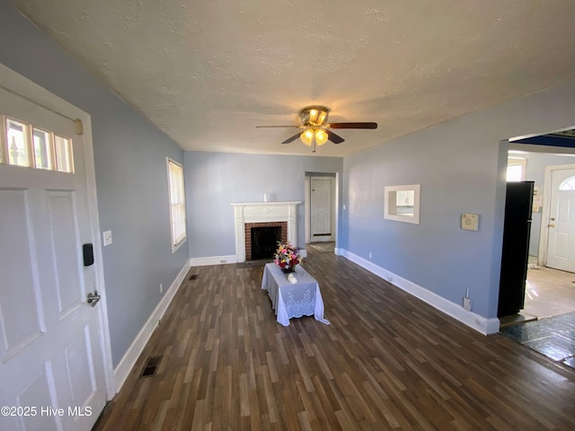 unfurnished living room with baseboards, a fireplace, wood finished floors, and a healthy amount of sunlight