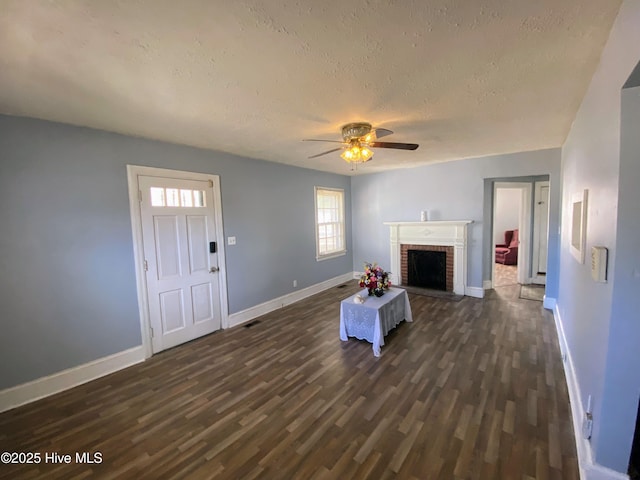 unfurnished living room featuring a brick fireplace, baseboards, dark wood finished floors, and a textured ceiling