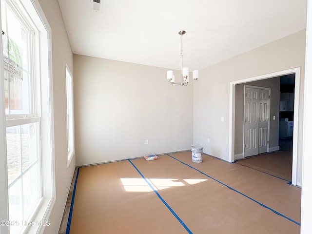 spare room featuring basketball hoop, an inviting chandelier, and plenty of natural light